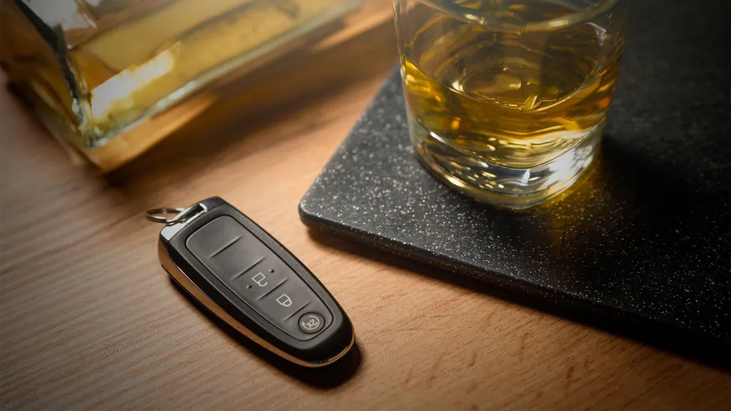 Car keys next to a glass of whiskey, representing a DUI charge