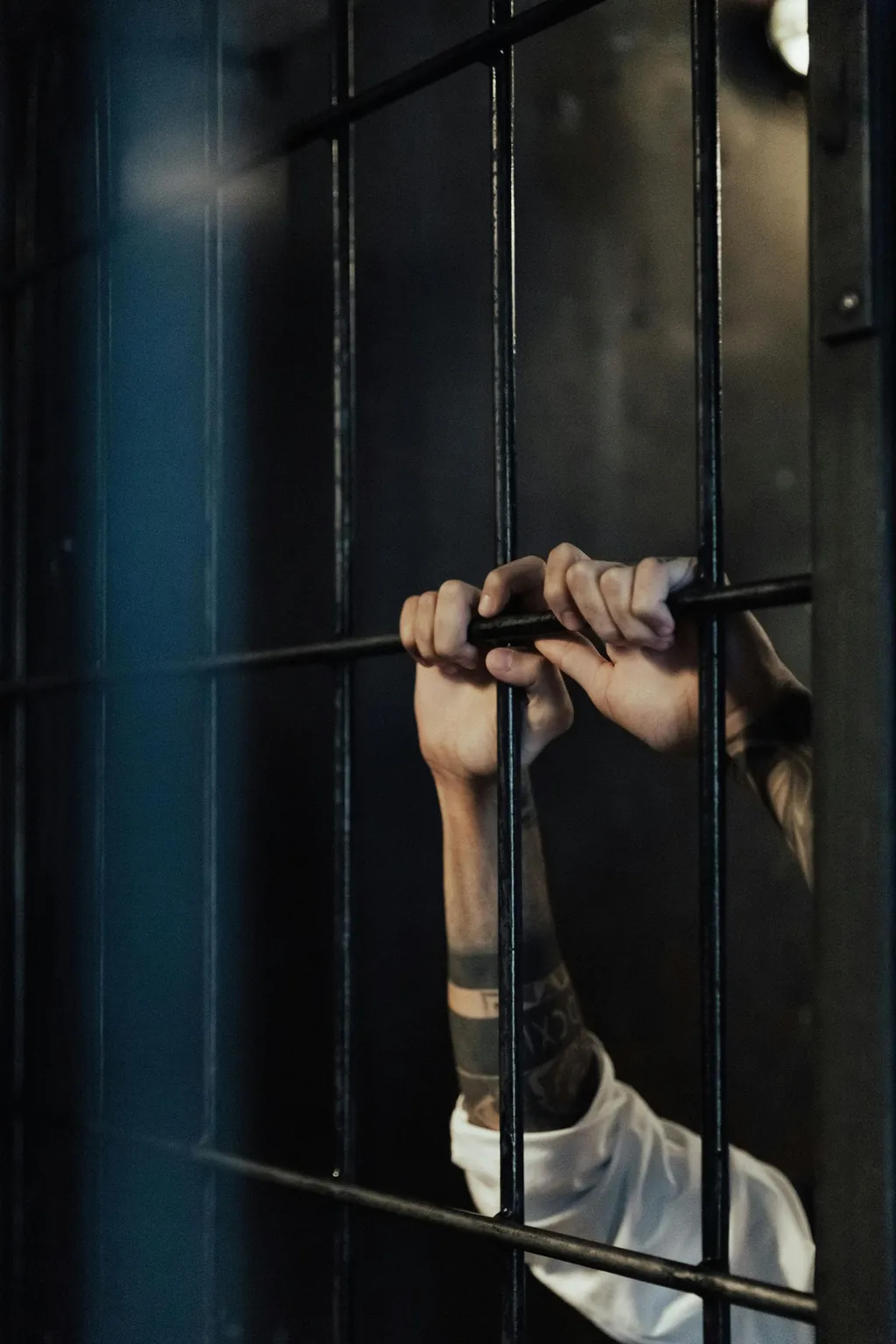 Hands gripping jail cell bars, representing criminal charges and jail time